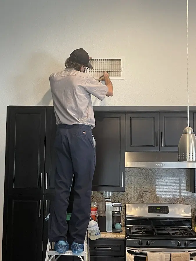 Technician inspecting an air vent during HVAC service in Pacific Grove